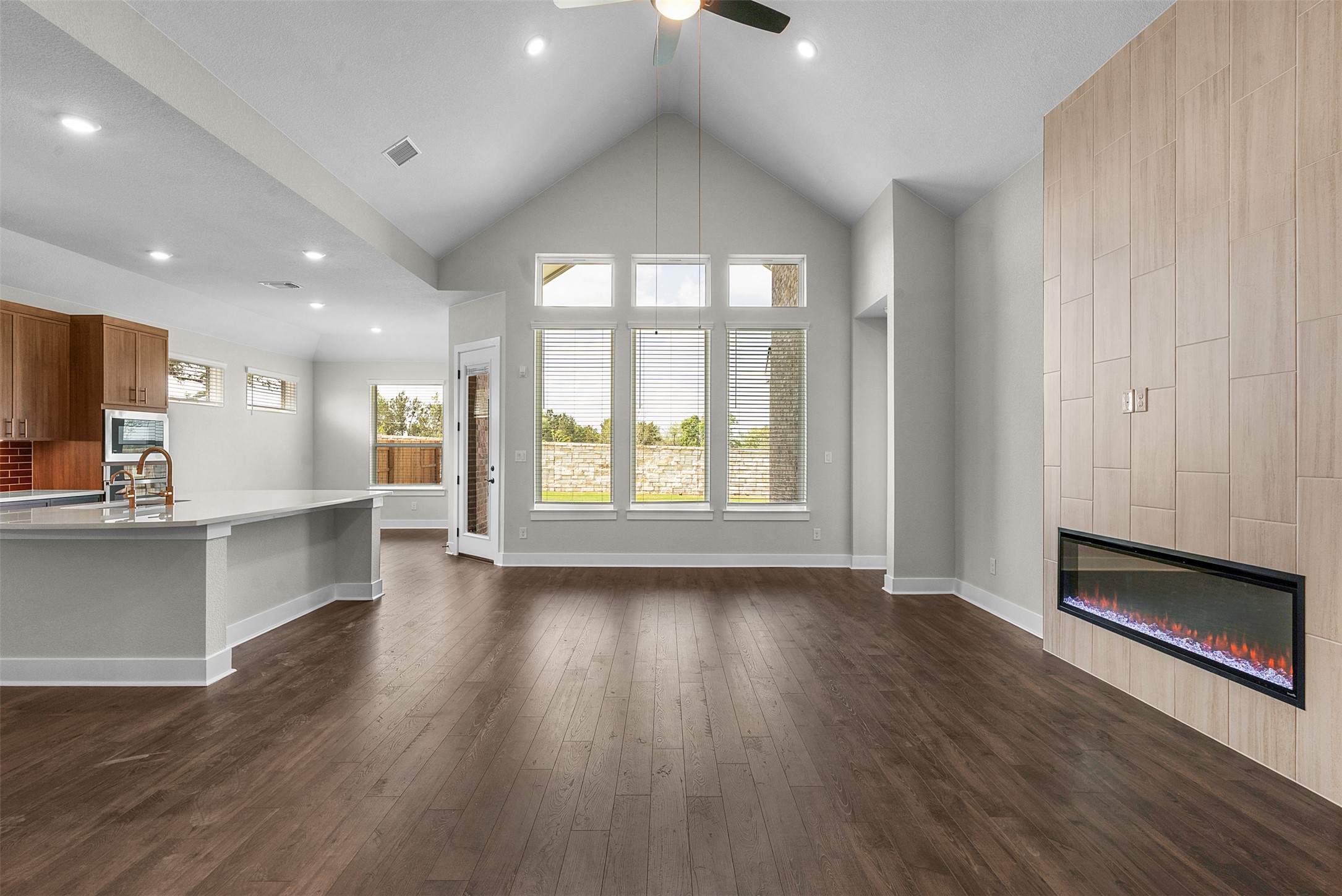 1121 Pansy Trail Georgetown, TX 78628 - Photo 7 of 25 Unfurnished living room with a tile fireplace, dark wood-style floors, a ceiling fan, a high ceiling, and recessed lighting