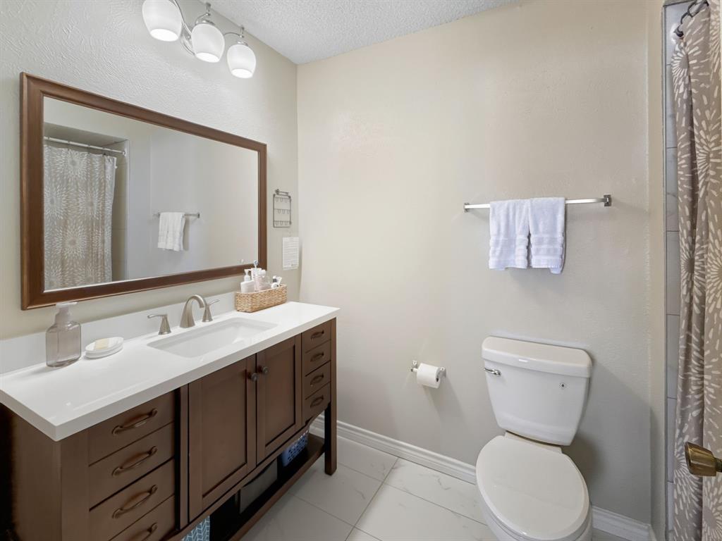 214 Samuel Boulevard, Unit 1H Coppell, TX 75019 - Photo 6 of 21 a bathroom with a toilet sink and mirror