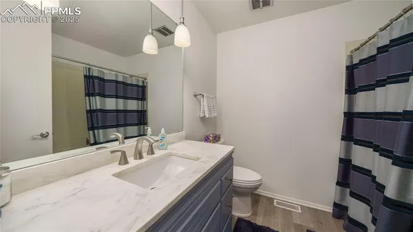 a bathroom with a granite countertop sink a toilet and shower