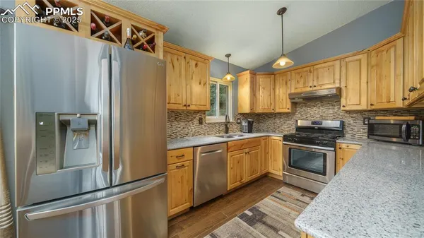 a kitchen with stainless steel appliances granite countertop a stove a sink and a refrigerator