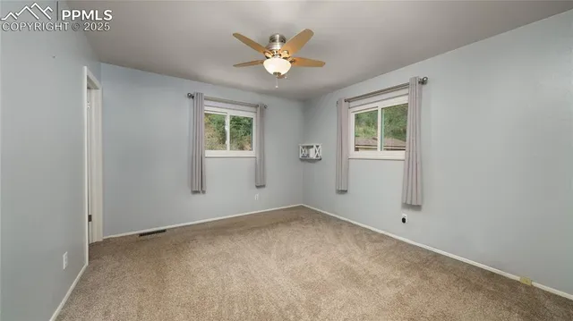 an empty room with windows and ceiling fan
