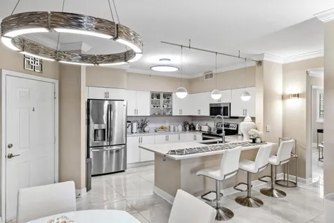 a kitchen with stainless steel appliances kitchen island granite countertop a refrigerator a sink a stove and white cabinets