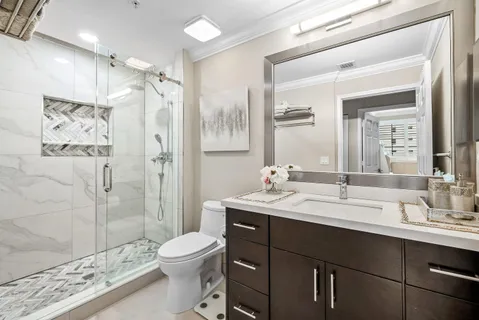 a bathroom with a double vanity sink toilet mirror and shower
