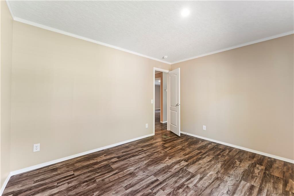 89 Ridge Road Seale, AL 36875 - Photo 28 of 46 Wood-finish flooring, neutral wall tones, crown molding, and a white interior door with a silver-tone handle