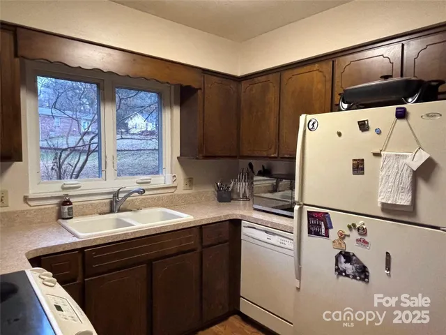 a white kitchen with sink a refrigerator and cabinets