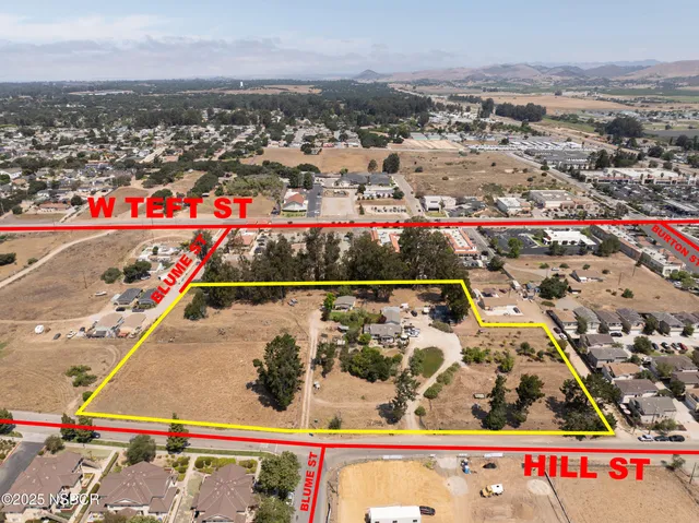 an aerial view of residential house with parking and trees