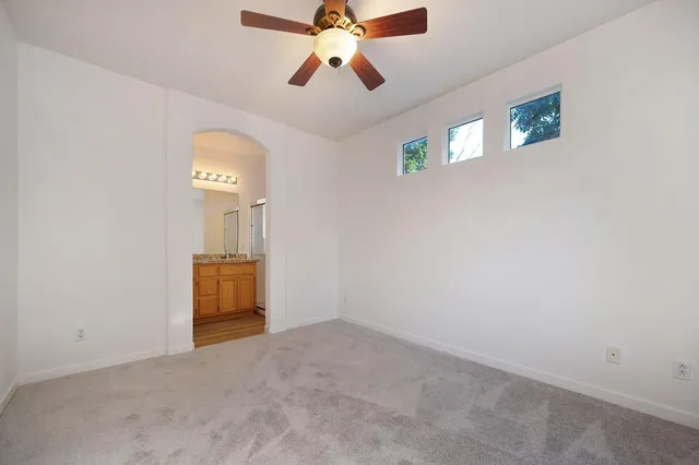 an empty room with a chandelier fan and windows