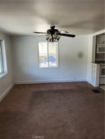 an empty room with windows and fan