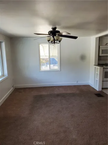 an empty room with windows and fan