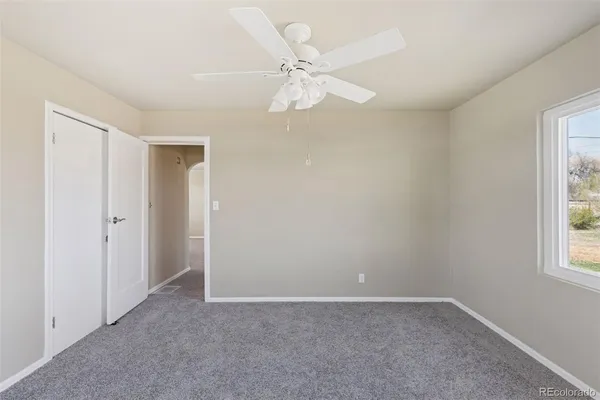 an empty room with windows and fan