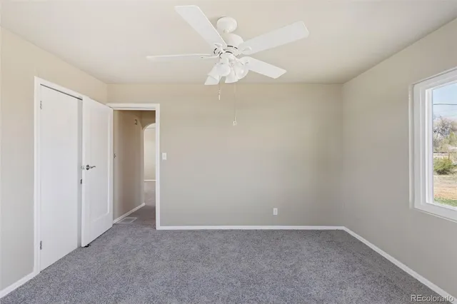 an empty room with windows and fan