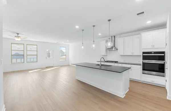 an empty room with wooden floor chandelier fan and windows