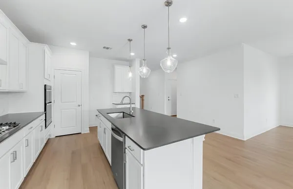 a kitchen with stainless steel appliances granite countertop a sink a microwave a stove and a wooden floors