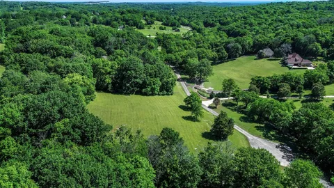 an aerial view of residential house with outdoor space and trees all around