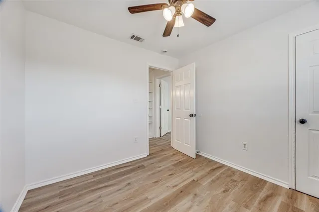 an empty room with wooden floor chandelier fan and closet area