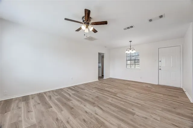 a view of empty room with wooden floor and window