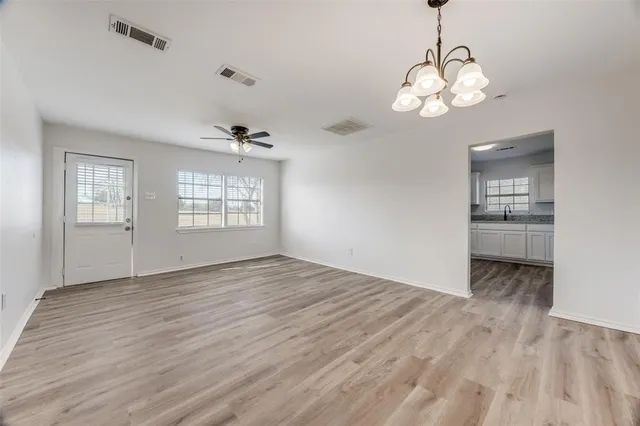 a view of an empty room with a window and wooden floor
