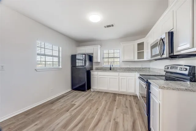 a kitchen with stainless steel appliances granite countertop a refrigerator and a stove top oven