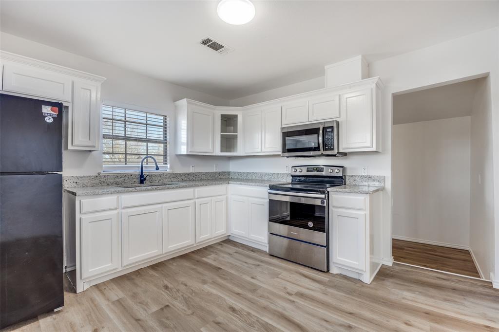 1382 Us Highway Denison, TX 75021 - Photo 7 of 25 a kitchen with granite countertop a refrigerator stove and microwave