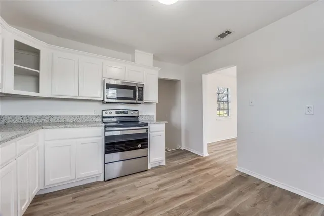 a kitchen with granite countertop white cabinets and stainless steel appliances