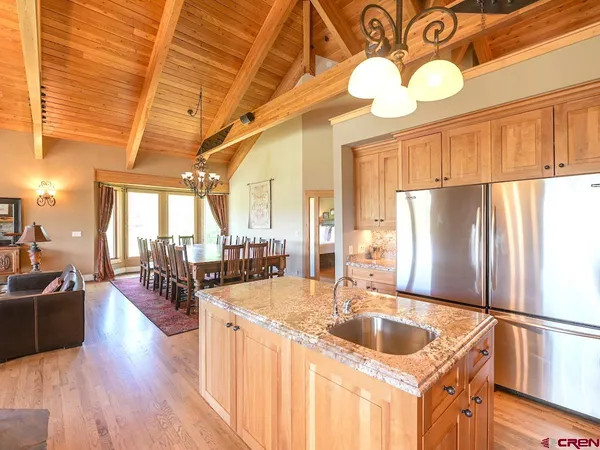 a kitchen with stainless steel appliances granite countertop a sink a refrigerator and couches