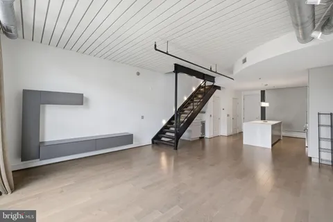 a view of an empty room with wooden floor and stairs