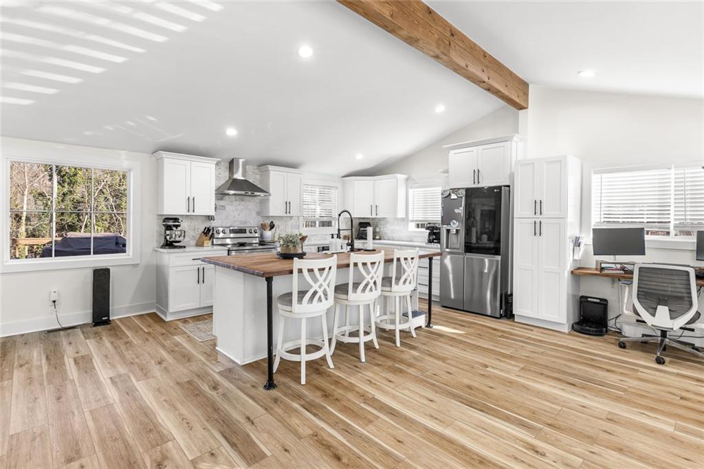 6120 Cardinal Drive Gainesville, GA 30506 - Photo 13 of 34 a kitchen with stainless steel appliances kitchen island granite countertop a refrigerator a stove a sink dishwasher and white cabinets with wooden floor