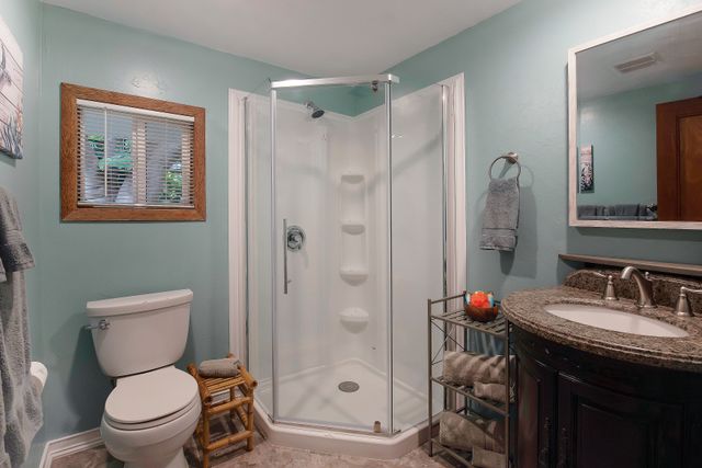 a bathroom with a granite countertop toilet sink shower and mirror