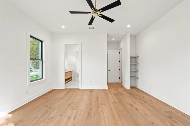 an empty room with windows and ceiling fan
