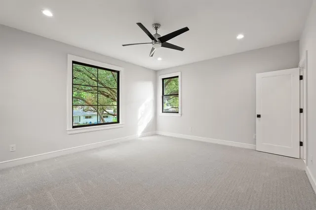 an empty room with windows and ceiling fan