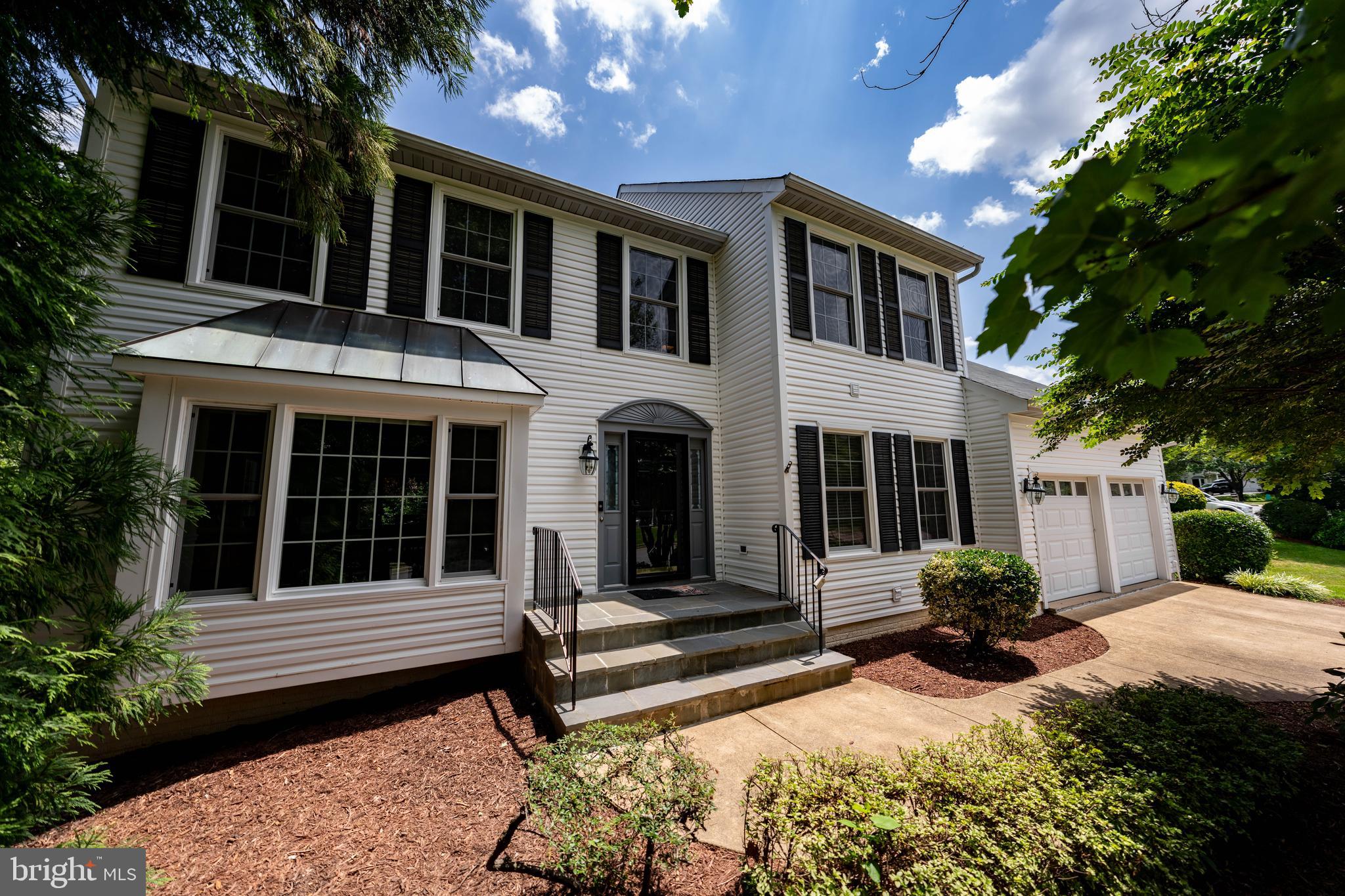 a view of a house with potted plants and a large tree