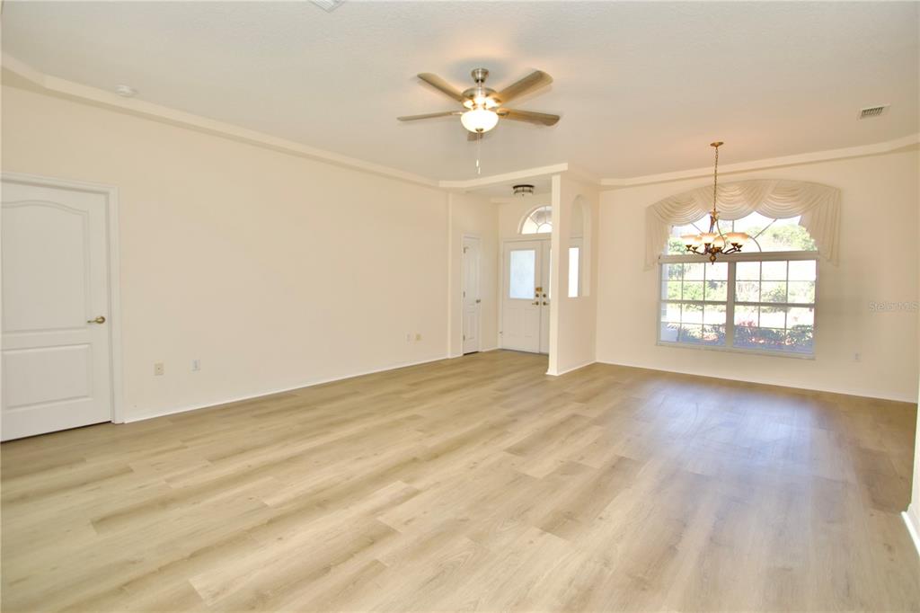 8056 Floral Drive Spring Hill, FL 34607 - Photo 11 of 29 an empty room with wooden floor chandelier fan and windows