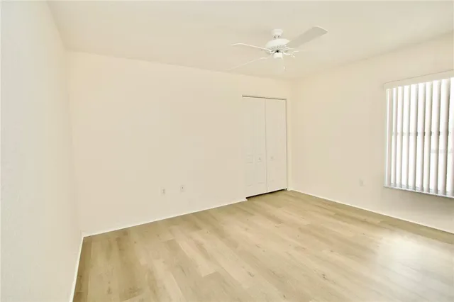 an empty room with a window and a ceiling fan