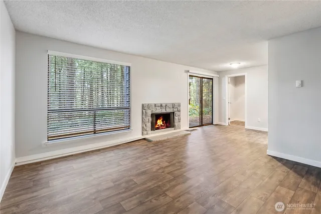 a view of empty room with wooden floor and fireplace