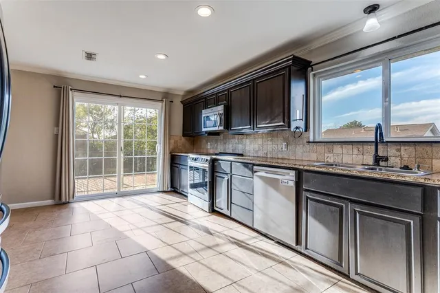 a kitchen with stainless steel appliances granite countertop a stove top oven a sink a counter space and cabinets