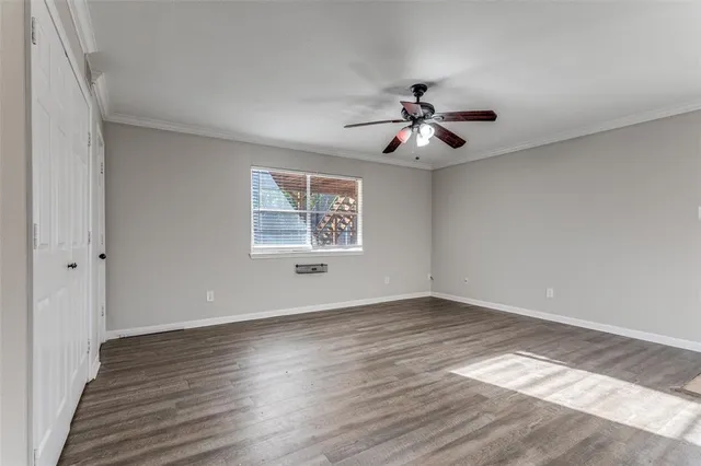 an empty room with wooden floor chandelier fan and windows
