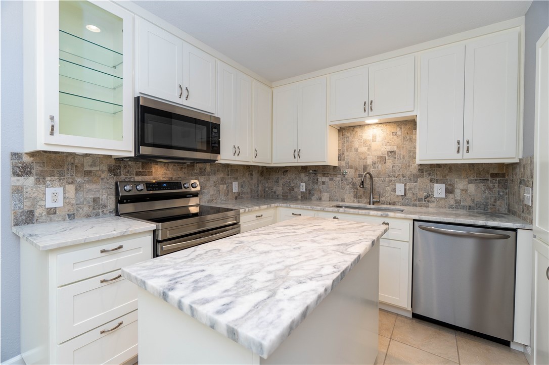 6232 Weber Road Corpus Christi, TX 78413 - Photo 5 of 23 a kitchen with kitchen island granite countertop a sink stainless steel appliances and white cabinets
