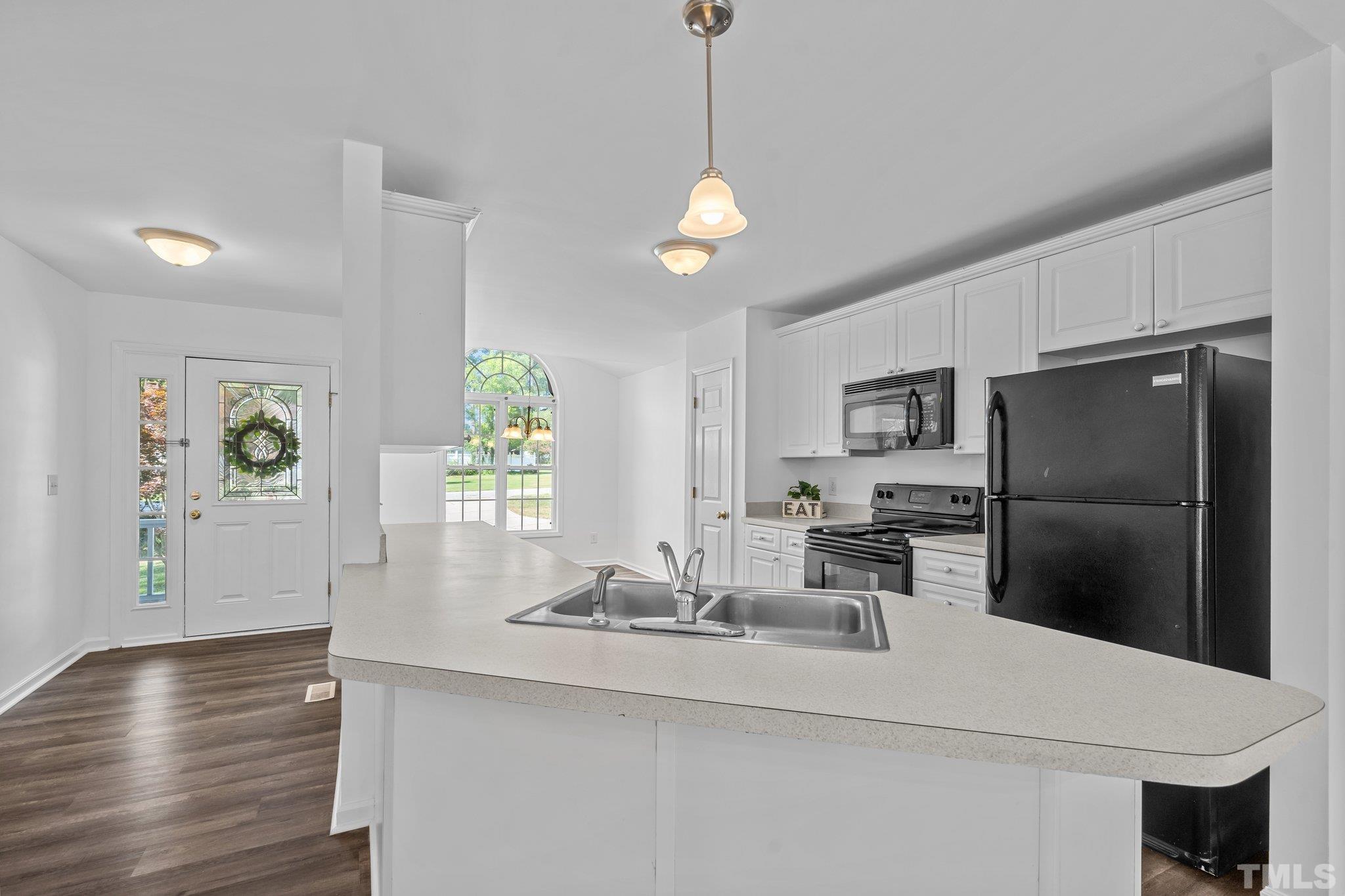302 Laurel Drive Smithfield, NC 27577 - Photo 12 of 38 a kitchen with stainless steel appliances granite countertop a sink a refrigerator a stove a dining table and chairs with wooden floor