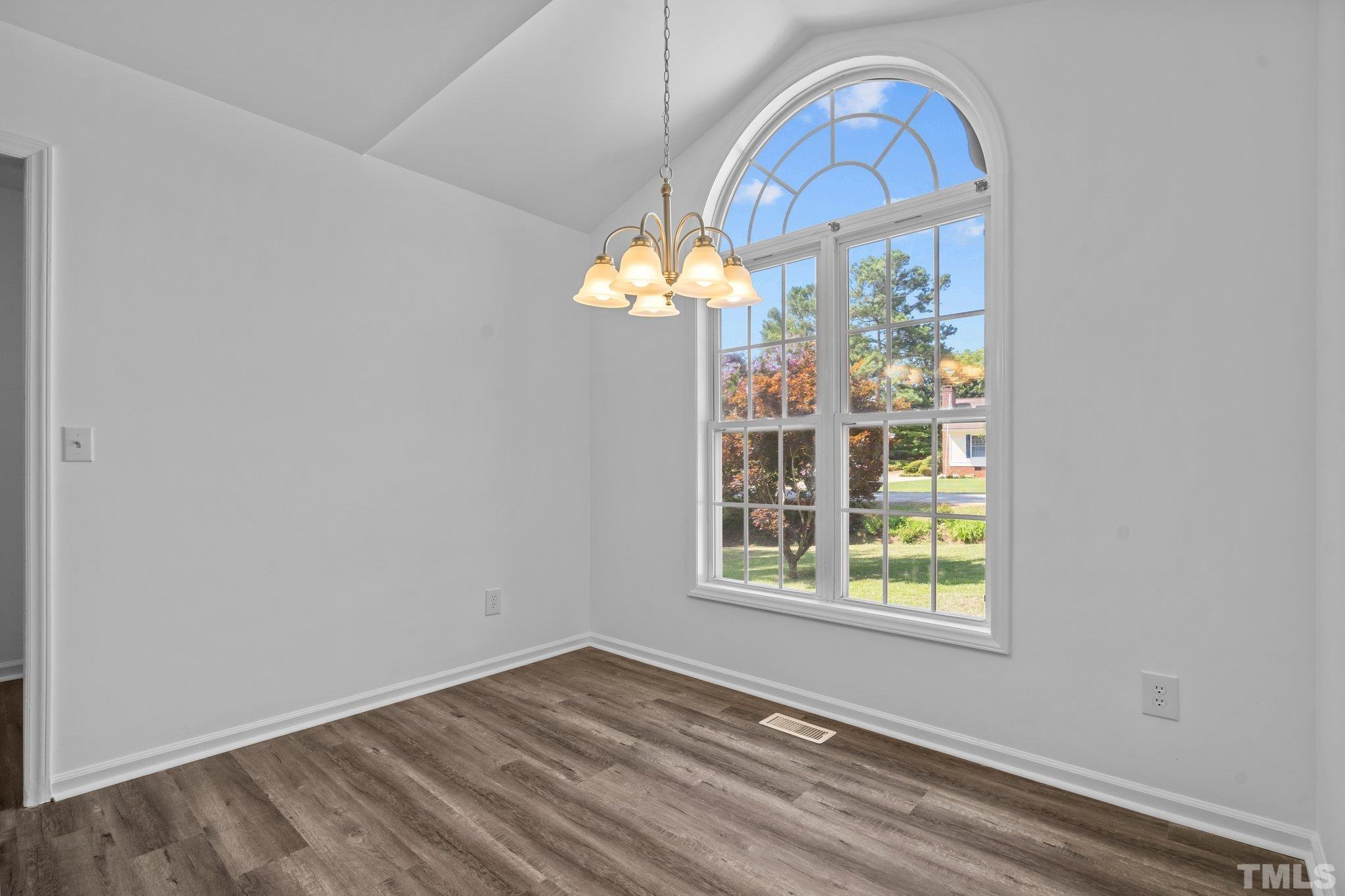 302 Laurel Drive Smithfield, NC 27577 - Photo 8 of 38 an empty room with wooden floor fan and windows