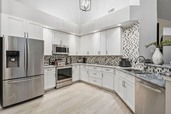 a kitchen with granite countertop white cabinets and stainless steel appliances