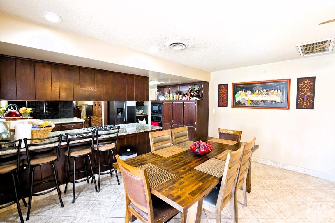 Undisclosed Address Bakersfield, CA 93309 - Photo 7 of 37 a kitchen with granite countertop a dining table chairs and a refrigerator