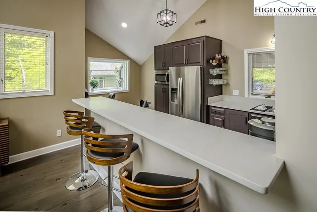 a kitchen with stainless steel appliances a dining table chairs and a refrigerator