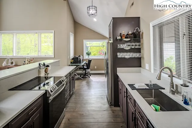 a kitchen with counter top space a sink a stove and wooden floor