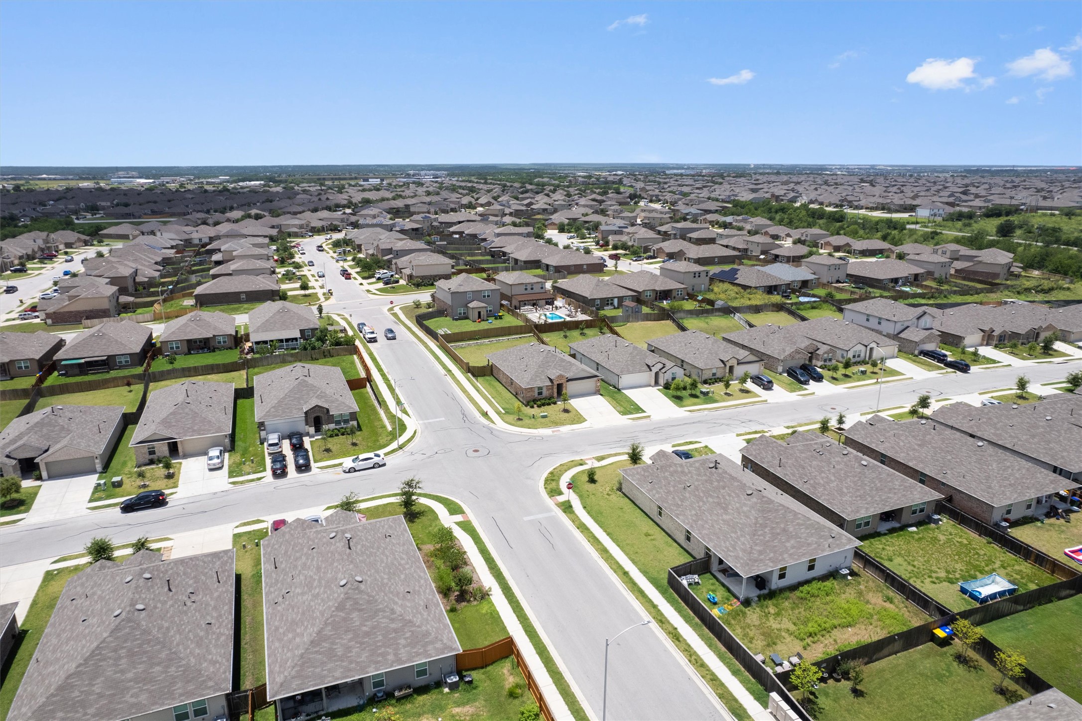 19525 Abigail Fillmore Road Manor, TX 78653 - Photo 33 of 38 An aerial perspective showcases a residential neighborhood with neatly arranged houses and streets under a broad sky.