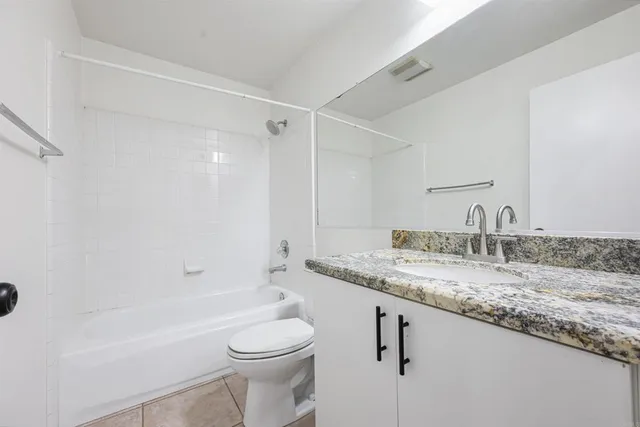 a bathroom with a granite countertop sink a toilet and shower