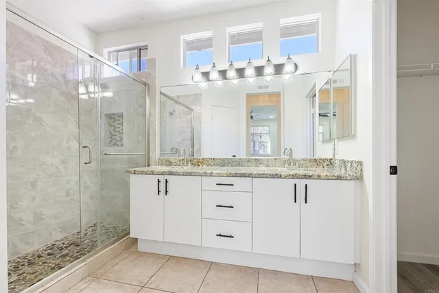 a bathroom with a granite countertop sink a mirror and a shower