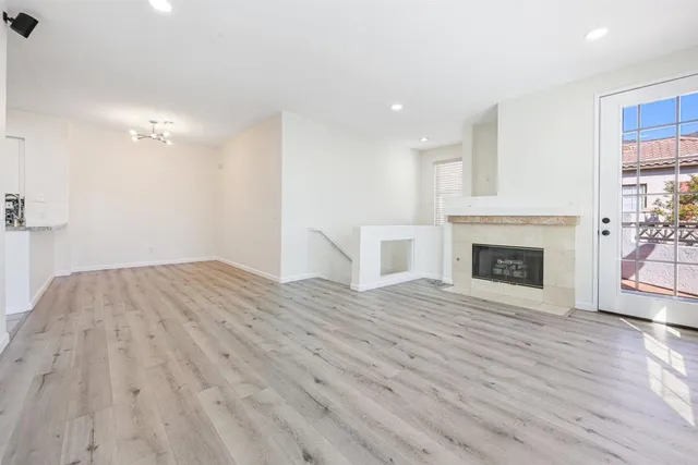 a view of empty room with wooden floor and fireplace