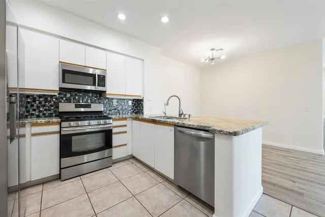 a kitchen with granite countertop a sink stainless steel appliances and cabinets