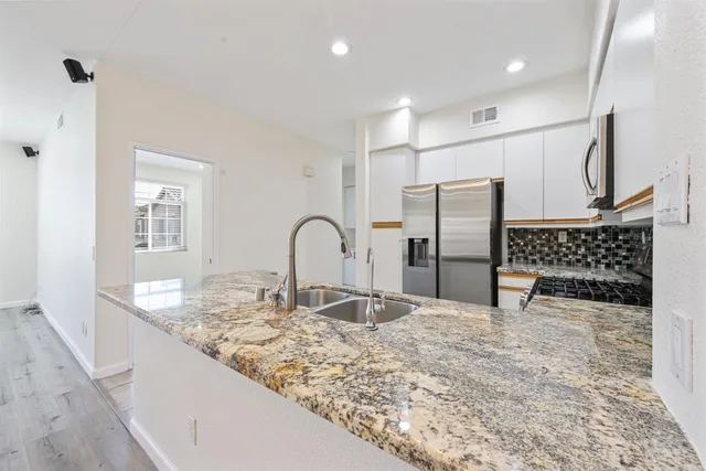 a kitchen with granite countertop a stove a sink and a refrigerator