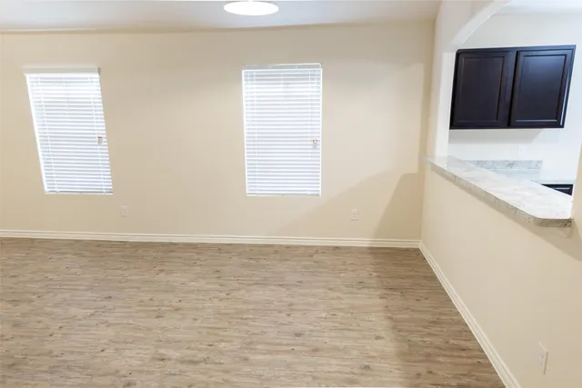 a view of an empty room with window and wooden floor